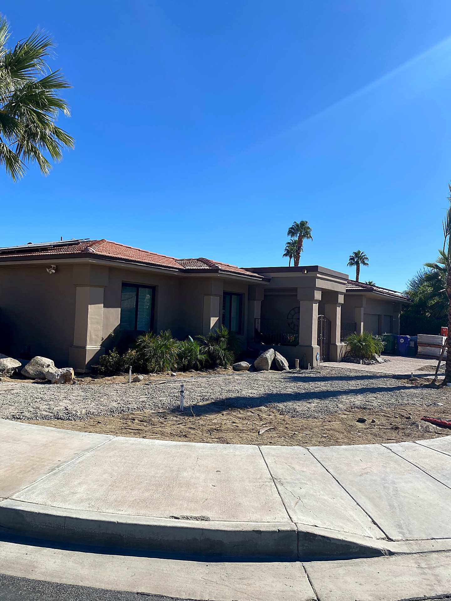 Front yard before landscaping — cleared lot with boulders and fresh gravel base