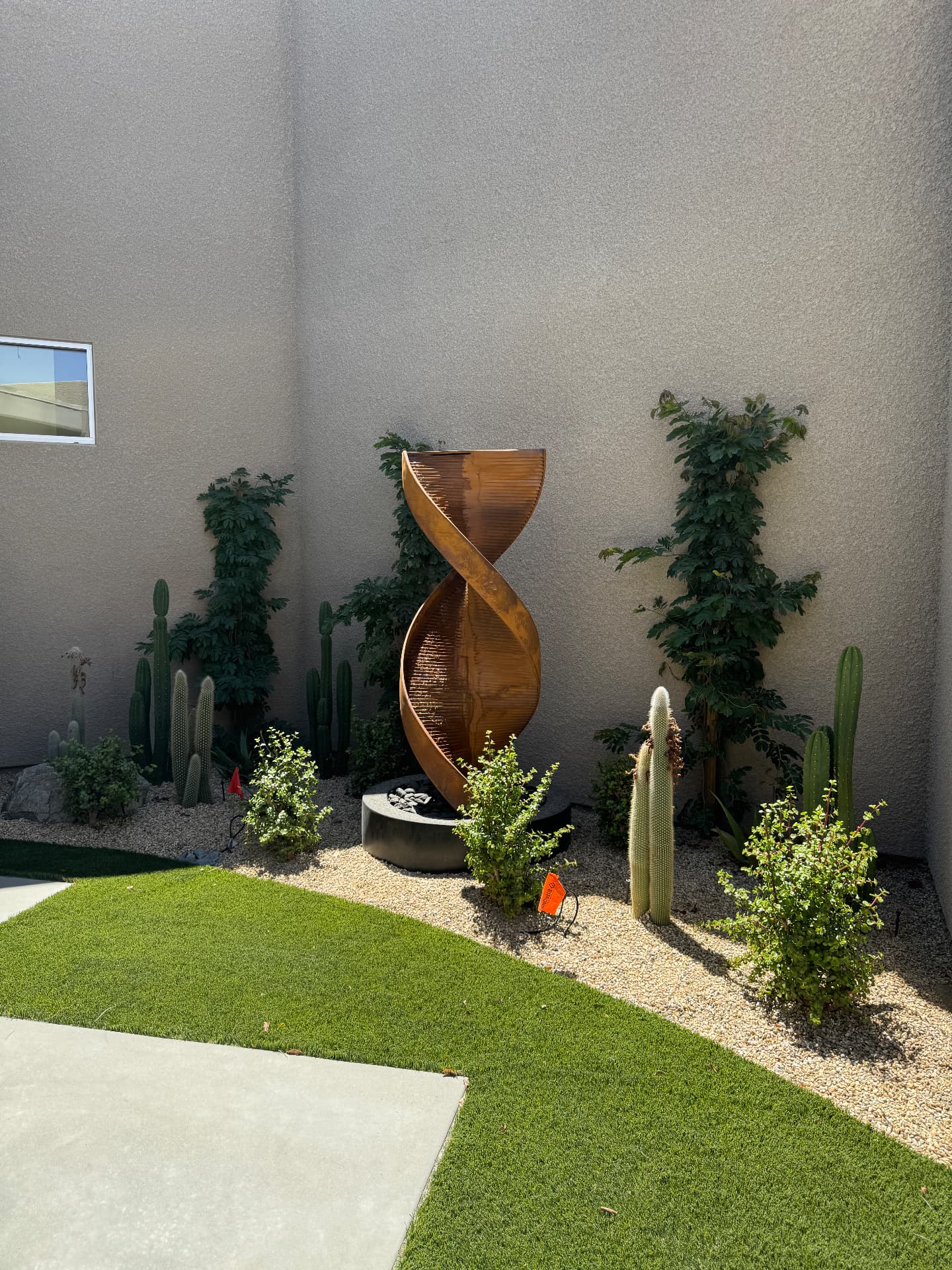 Copper spiral sculpture among cactus and bougainvillea